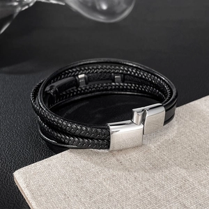 Detail of multi-layer black braided leather bracelet with silver magnetic metal clasp