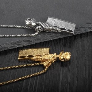 Detailaufnahme des gotischen Totenkopf-Anhängers mit Metzgermesser an einer Box-Kette in Gold