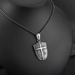 Detailed close-up of retro shield pendant with cross relief and vintage floral engraving