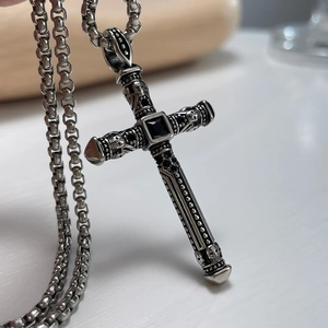 Macro shot of gothic steel cross pendant with black gem and skull relief details