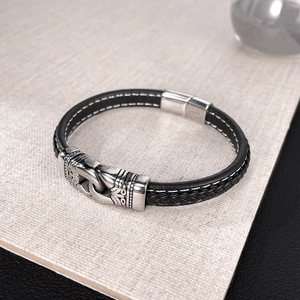 Détail du bracelet en cuir noir tressé avec ornement tribal en acier inoxydable