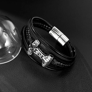 Close-up of men's multi-layer black leather bracelet with silver Mjolnir hammer charm