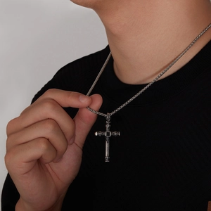Close-up of vintage steel cross pendant with black gemstone on male model