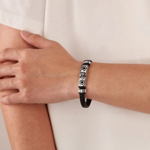 Détail du bracelet punk en cuir tressé avec un emblème de tête de léopard en argent ciselé