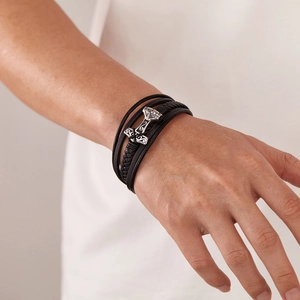 Detailed close-up of a men's multilayered black leather bracelet with a silver Mjolnir charm