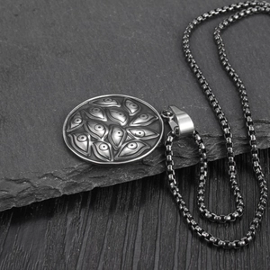 Macro view of stainless steel Evil Eye pendant necklace on grey stone and wood