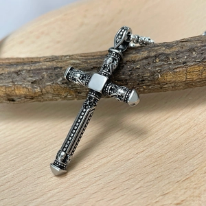 Retro stainless steel cross pendant necklace with gothic skull details on wood