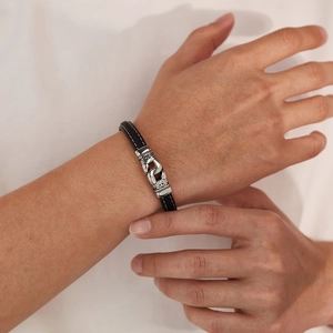 Détail d'un bracelet en cuir tressé noir avec fermoir gravé en acier inoxydable argenté
