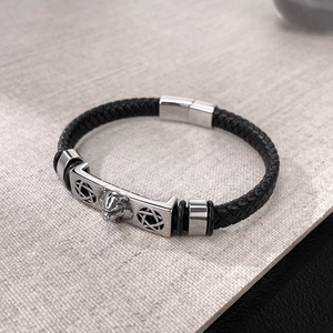 Détail d'un pendentif tête de lion en acier sur bracelet en cuir noir tressé