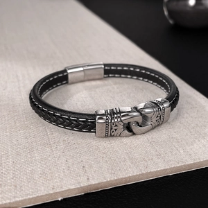 Détail d'un bracelet en cuir pour homme avec cordon tressé, couture blanche et fermoir aimanté