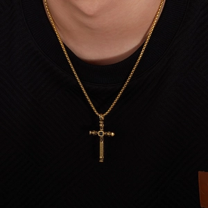 Detailed view of men's gold cross necklace with black gemstone and embossed details