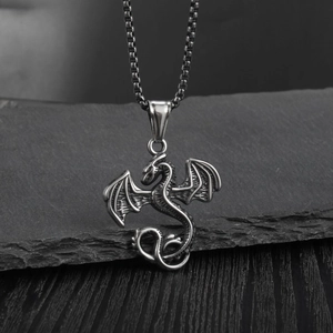 Détail du pendentif dragon argenté vintage avec ailes sur une surface en pierre texturée