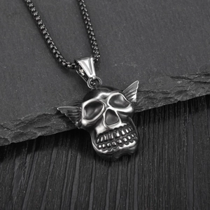 Gothic winged skull pendant necklace in matte black stainless steel on slate background