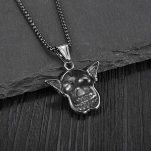 Gothic skull pendant necklace with bat wings in gunmetal finish on a dark rock