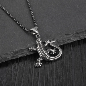 Retro stainless steel lizard pendant necklace with oxidized details on a black stone surface