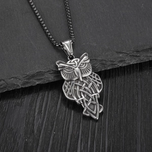 Retro stainless steel owl pendant necklace with Celtic knot patterns on a rock surface