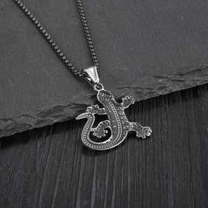Vintage stainless steel gecko lizard pendant necklace with black spots on a dark surface