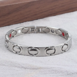Detailopname van zilveren magnetische therapie armband met rode en witte energie-inzetstukken