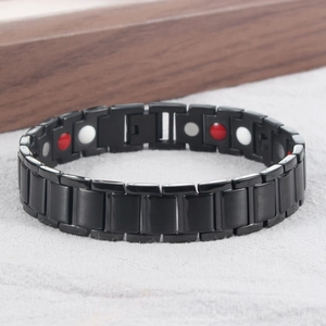 Detail view of black magnetic therapy bracelet with inset health stones on dark wood