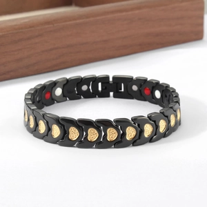 Detail of magnetic therapy bracelet with golden heart patterns on black metal links