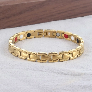 Dettaglio di un bracciale magnetico dorato con inserti colorati su fondo in tessuto grigio