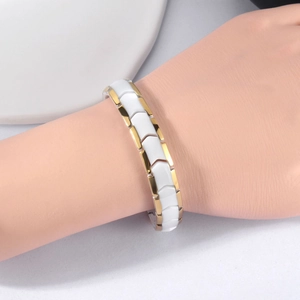 Bracelet magnétique moderne en céramique blanche et métal doré porté au poignet