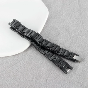 Close-up of black H-shaped link bracelet with silver clasp on white ceramic plate