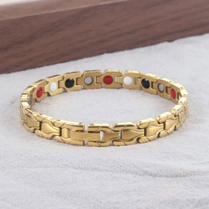 Dettaglio del bracciale magnetico dorato con inserti funzionali rossi, neri e bianchi