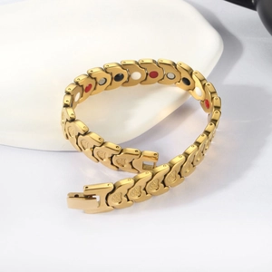 Golden magnetic heart bracelet with fish scale links on white decorative stone