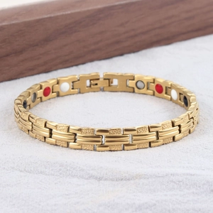 Detail eines goldenen Titan-Magnettherapie-Armbands mit Punktstreifen auf Holzgrund