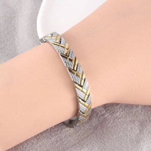 Macro detail of bi-color metal bracelet with textured silver and polished gold V-links