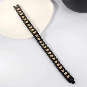 Detail of black and gold magnetic bracelet with embossed heart patterns on ceramic plate