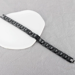 Polished black magnetic health bracelet with rectangular chain links on a white plate