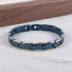 Detail eines kugelförmigen Magnetarmbands in Blau und Gold auf grauem Leinenstoff