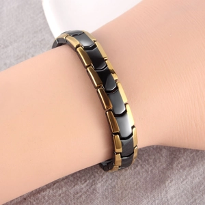 Detail of magnetic therapy bracelet with gold metal links and black ceramic arrows