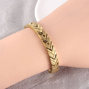 Detailed macro shot of a gold-plated magnetic arrow bracelet with mesh textured pattern