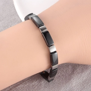 Dettaglio di un bracciale magnetico in acciaio e ceramica nera su un modello di mano