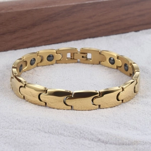 Detail eines kugeligen goldfarbenen Magnetarmbands mit Puzzle-Gliedern und schwarzen Magneten