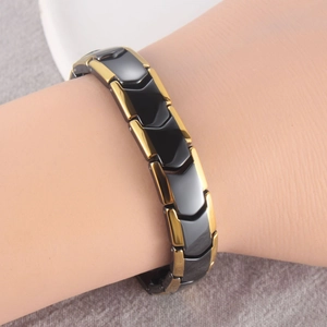 Detailed view of black ceramic and gold metal magnetic bracelet worn on the wrist