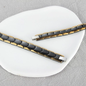 Magnetic black ceramic and gold metal chain link bracelet on a stone display plate