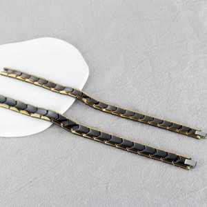 Macro shot of magnetic therapy bracelet with black and gold V-shaped metal link texture