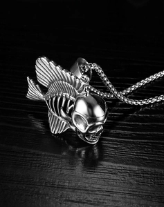 Close-up of a punk style fish skeleton and skull pendant on a sleek box chain necklace