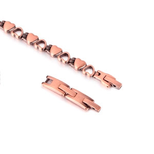 Detail of red copper magnetic bracelet featuring hollow heart links and folding clasp
