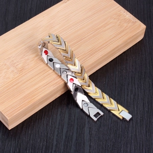 Men's two-tone arrow pattern magnetic bracelet with gold finish on wood background