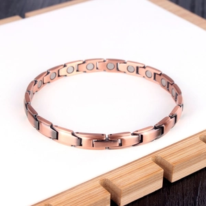 Bracelet de santé magnétique en cuivre rose pour femme sur un support en bambou
