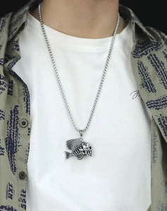 Punk style men's fish skeleton skull pendant on box chain worn over a camo shirt