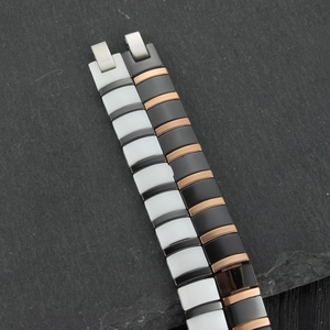 Close-up of ceramic and metal link bracelets with folding safety clasps on slate background