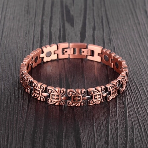 Vintage red copper magnetic bracelet with cross patterns on a dark wooden background