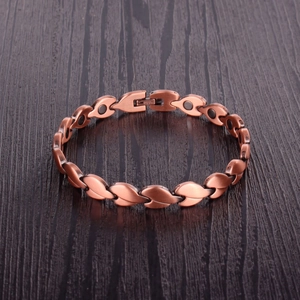 Copper magnetic therapy bracelet with leaf design and magnetic stones on wood surface