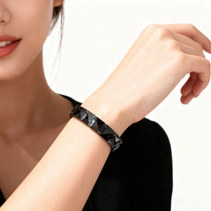 Macro view of a geometric faceted black ceramic bracelet with glossy finish on a wrist
